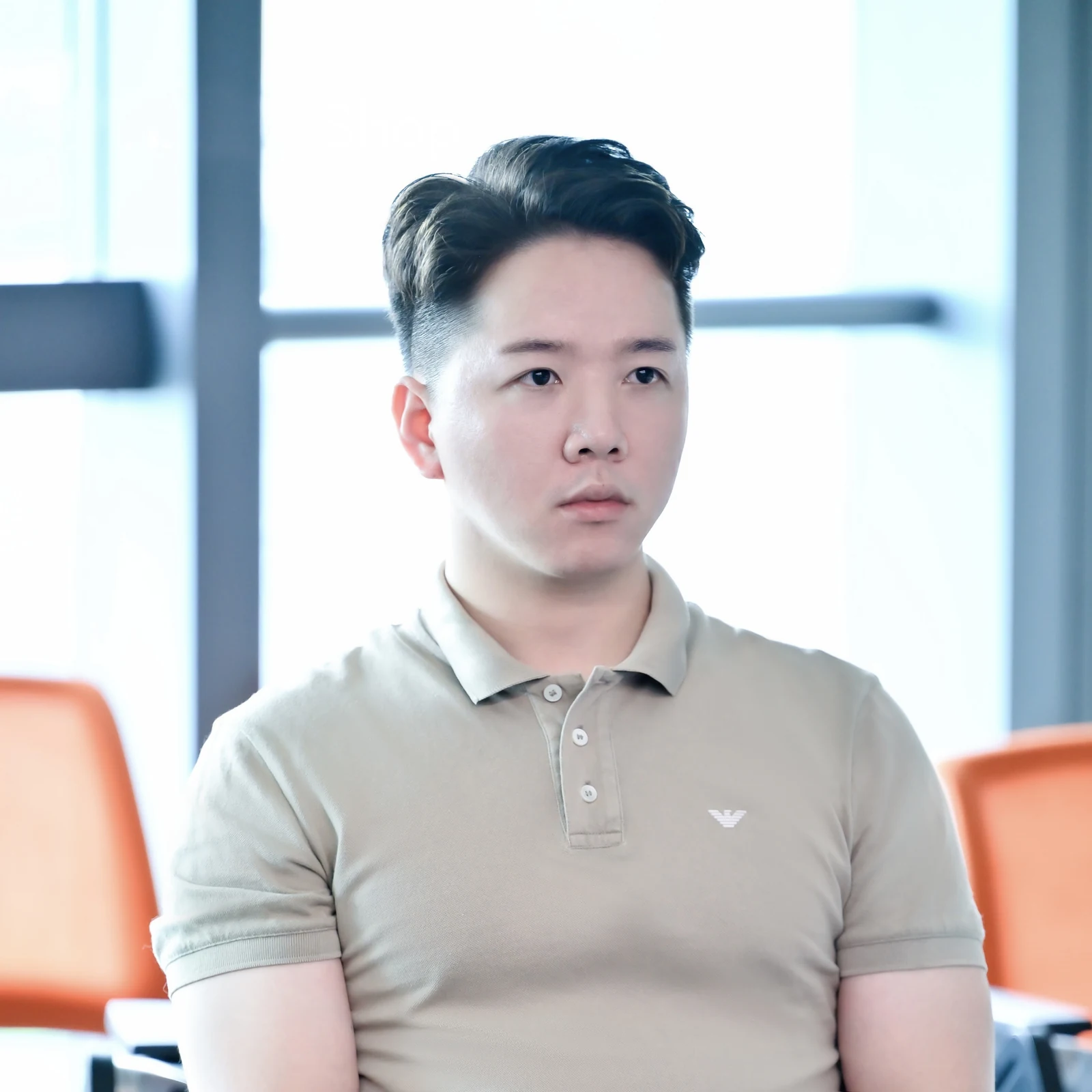 张应善身穿浅色 Polo 衫坐在窗边